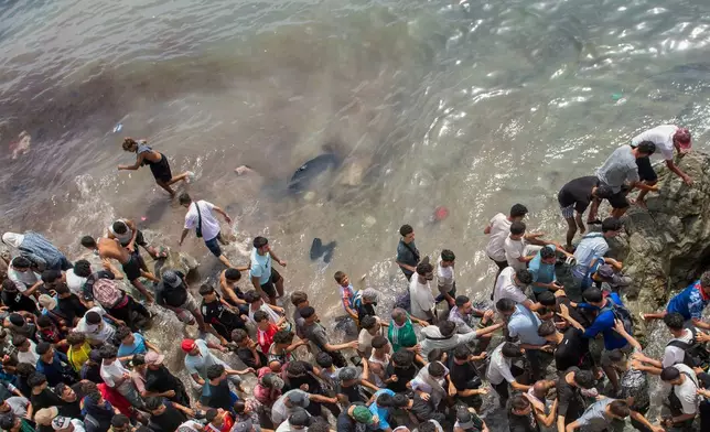 People walk on a beach as they attempt to cross from the Moroccan northern town of Fnideq to the Spanish enclave of Ceuta, Friday, July 31, 2026. (AP Photo)