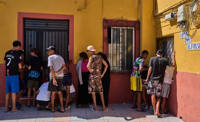 Migrants, some of them unaccompanied minors, who crossed from Morocco into Spain, write down their contact information to give to a neighborhood association in the Spanish enclave of Ceuta, Tuesday, Aug. 4, 2026. (AP Photo/Bernat Armangue)