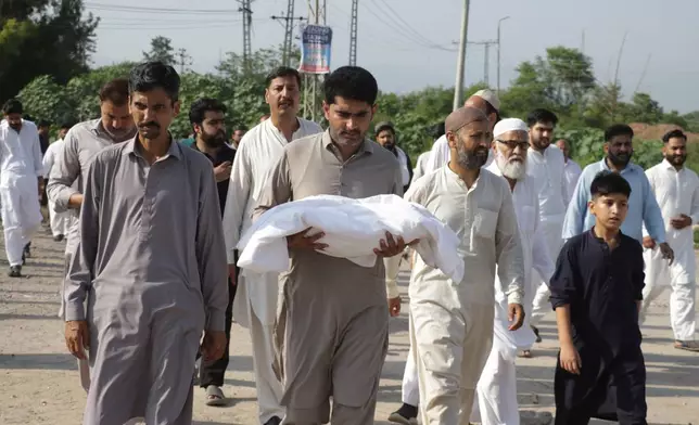A man carries the body of a newborn for burial after the child died in a fire at a hospital in Islamabad, Pakistan, Wednesday, Aug. 26, 2026. (AP Photo/Ehsan Shahzad)