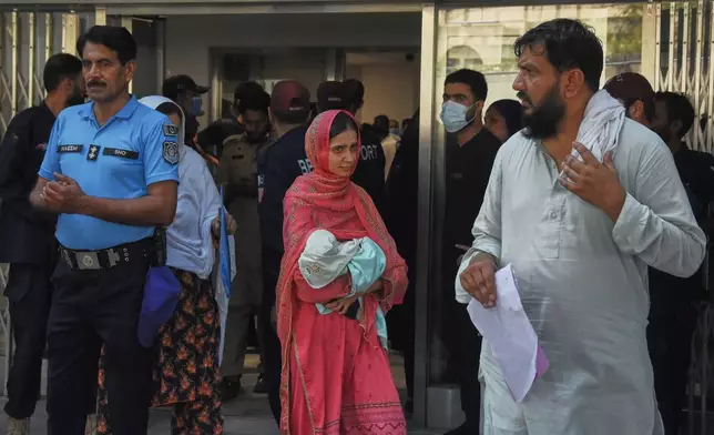 A woman carries her newborn baby out from a nursery in the gynecology ward of a hospital following a fire in Islamabad, Pakistan, Wednesday, Aug. 26, 2026. (AP Photo)