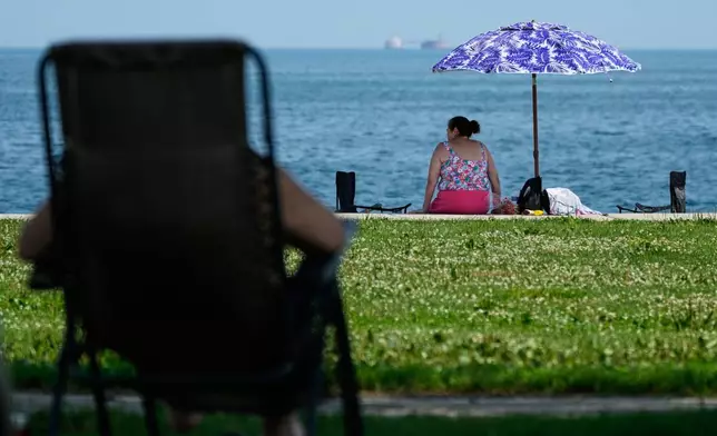 FILE - A woman cools off under a umbrella during hot weather at Montrose beach in Chicago, July 15, 2026. (AP Photo/Nam Y. Huh, File)