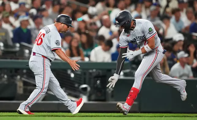 Minnesota Twins' Royce Lewis, right, celebrates with third base coach Ramon Borrego (46) after hitting a solo home run against the Seattle Mariners during the seventh inning of a baseball game, Friday, July 31, 2026, in Seattle. (AP Photo/Lindsey Wasson)