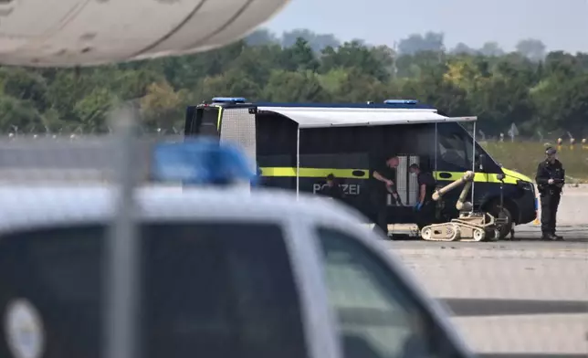 Police forensic technicians prepare to deploy an explosive-disposal robot near a Ukrainian aircraft at Leipzig/Halle Airport, in Schkeuditz, Germany, Wednesday Aug. 5, 2026, where flight operations were suspended overnight after a drone sighting was reported and another object was found near a runway. (Hendrik Schmidt/dpa via AP)