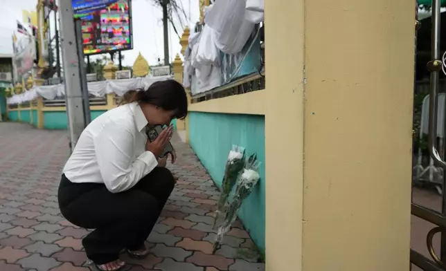 A woman lays flowers and offers prayers at Debsirin Nonthaburi School, a day after the shooting at the school in Nonthaburi province, Thailand, on Saturday, Aug. 8, 2026. (AP Photo/Sakchai Lalit)
