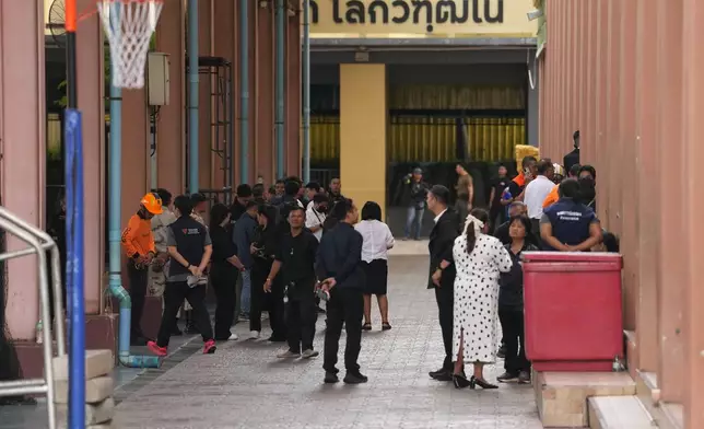 First responders and others stand inside after a shooting at the Debsirin Nonthaburi School in Thailand's Nonthaburi province, Friday, Aug. 7, 2026. (AP Photo/Sakchai Lalit)