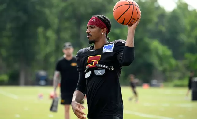 Washington Commanders quarterback Jayden Daniels works out before a joint practice with the Miami Dolphins at NFL football training camp, Wednesday, Aug. 12, 2026 in Ashburn, Va. (AP Photo/Nick Wass)