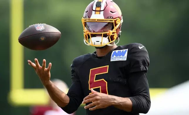 Washington Commanders quarterback Jayden Daniels works out before a joint practice with the Miami Dolphins at NFL football training camp, Wednesday, Aug. 12, 2026 in Ashburn, Va. (AP Photo/Nick Wass)