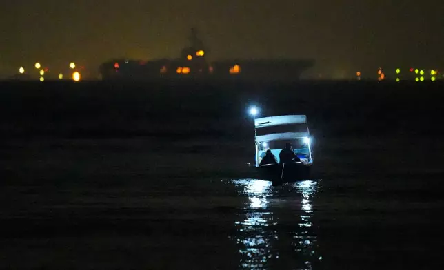 Fishermen sit in their boat as the the U.S. Navy aircraft carrier USS Abraham Lincoln is seen in the background in Batam, Indonesia, Sunday, Aug. 30, 2026. (AP Photo/Dita Alangkara)