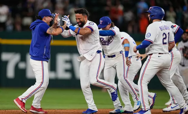 Texas Rangers' Alejandro Osuna, left, Ezequiel Duran, second from left, and the rest of the team celebrate Duran's run-scoring single in the ninth inning a baseball game against the San Francisco Giants in Arlington, Texas, Tuesday, Aug. 4, 2026. (AP Photo/Tony Gutierrez)