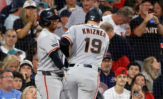 San Francisco Giants' Andrew Knizner (19) is congratulated by teammate Rafael Devers, left, after hitting a home run during the third inning of a baseball game against the Boston Red Sox, Saturday, Aug. 22, 2026, in Boston. (AP Photo/Mary Schwalm)