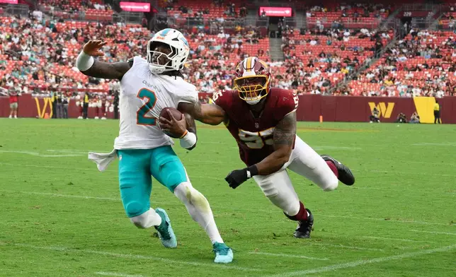 Washington Commanders defensive tackle Byron Cowart (55) grabs Miami Dolphins quarterback Malik Willis (2) during the first half of an NFL preseason football game, Friday, Aug. 14, 2026, in Landover, MD. (AP Photo/Nick Wass)