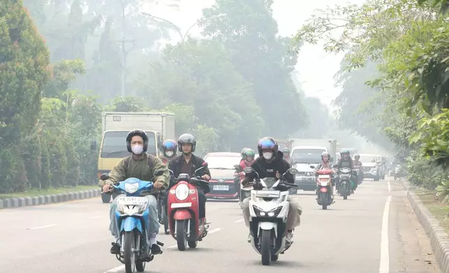 Motorists ride on a road as haze from wildfires blanket the city of Pontianak, West Kalimantan, Indonesia, Friday, Aug. 21, 2026. (AP Photo/Stefanus Taman)