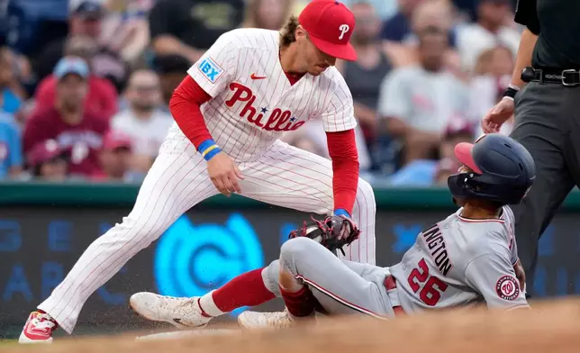 Philadelphia Phillies third baseman Bryson Stott, left, tags out Washington Nationals' Nasim Nuñez after he tries to steal third during the third inning of a baseball game Tuesday, Aug. 4, 2026, in Philadelphia. (AP Photo/Matt Slocum)