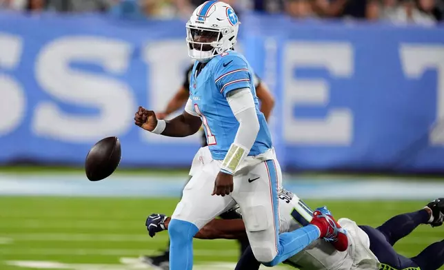 Tennessee Titans quarterback Cam Ward (1) fumbles the ball as he is hit by Seattle Seahawks linebacker Chazz Surratt during the first half of a preseason NFL football game, Sunday, Aug. 23, 2026, in Nashville, Tenn. (AP Photo/George Walker IV)