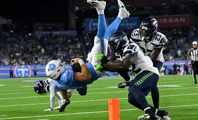 Tennessee Titans quarterback Will Levis (8) is tackled by Seattle Seahawks linebacker Aaron Smith (42) and safety D'Anthony Bell (23) during the second half of a preseason NFL football game, Sunday, Aug. 23, 2026, in Nashville, Tenn. (AP Photo/John Amis)