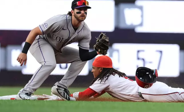 Washington Nationals' CJ Abrams, right, slides into second base for a steal ahead of a tag by Colorado Rockies second baseman Connor Norby during the first inning of a baseball game in Washington, Monday, Aug. 24, 2026. (AP Photo/Terrance Williams)