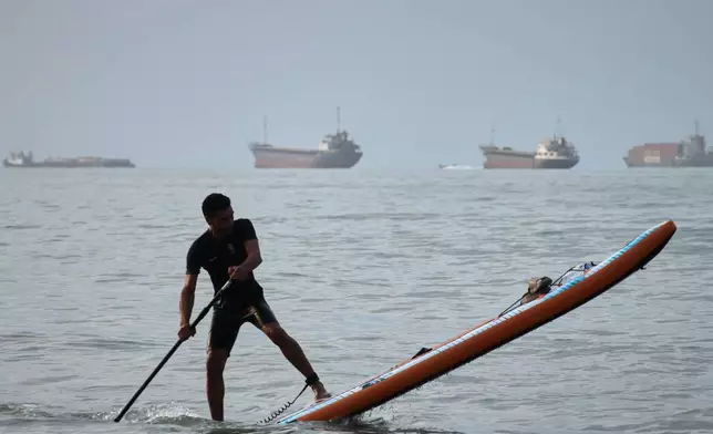 A man paddles a stand-up paddleboard as cargo ships and other commercial vessels appear anchored in the Strait of Hormuz off Bandar Abbas, Iran, Monday, July 27, 2026. (Razieh Poudat/ISNA via AP)