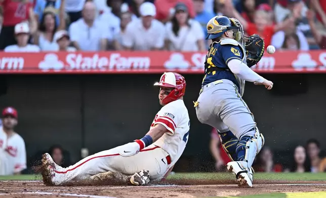 Los Angeles Angels' Mike Trout, left, slides to score during the first inning of a baseball game against the Milwaukee Brewers, Saturday, Aug. 1, 2026, in Anaheim, Calif. (AP Photo/William Liang)