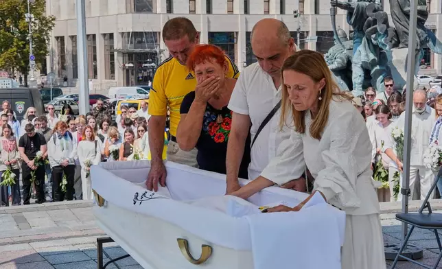 Relatives mourn near the coffin of Vitalina Yarovenko, 20, during the funeral ceremony in the Independence square in Kyiv, Ukraine, Tuesday, Aug. 4, 2026. (AP Photo/Efrem Lukatsky)