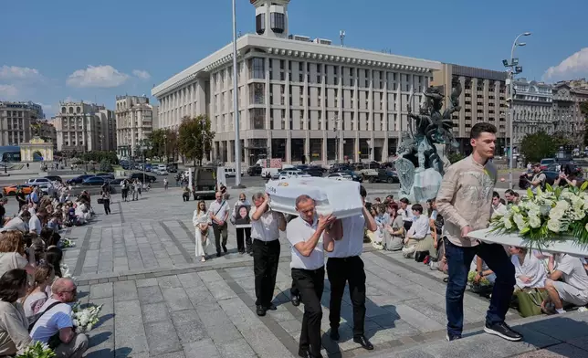 People kneel during the funeral ceremony for Vitalina Yarovenko, 20, in the Independence square in Kyiv, Ukraine, Tuesday, Aug. 4, 2026. (AP Photo/Efrem Lukatsky)