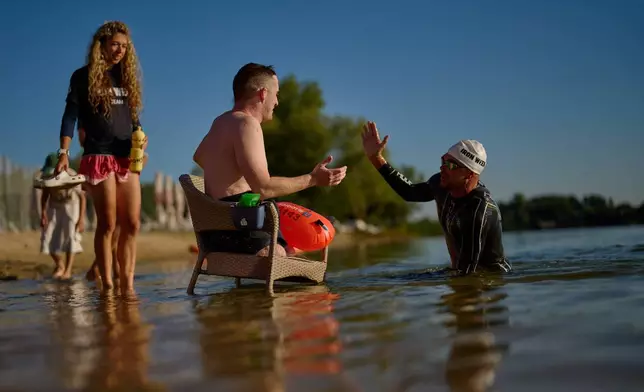 Ukrainian war veteran Maxim Yuzvyak, left, is greet by sport celebrity Danylo Sapunov during a sporting event to encourage people and injured soldiers to take part in sports at a lake on the outskirts of Kyiv, Monday, Aug. 24, 2026, during the 35th anniversary of Ukraine's Independence Day. (AP Photo/Francisco Seco)