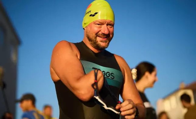 Ukrainian war veteran Evheny Lakhnenko puts on his goggles during a sporting event to encourage people and injured soldiers to do sports in a lake at on the outskirts of Kyiv, Monday, Aug. 24, 2026, during the 35th anniversary of Ukraine's Independence Day. (AP Photo/Francisco Seco)