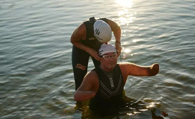 Ukrainian war veteran Oleksii Kozak is helped to put on his goggles during a sporting event to encourage people and injured soldiers to take part in sports at a lake on the outskirts of Kyiv, Monday, Aug. 24, 2026, during the 35th anniversary of Ukraine's Independence Day. (AP Photo/Francisco Seco)