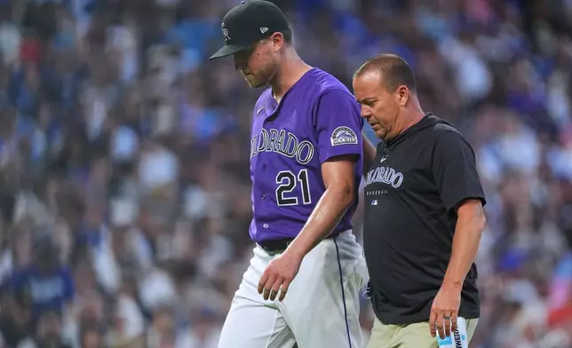 Colorado Rockies starting pitcher Kyle Freeland, back, is escorted to the clubhouse by trainer Heath Townsend after Freeland was pulled from the mound because of injury in the fourth inning of a baseball game against the Los Angeles Dodgers Wednesday, Aug. 19, 2026, in Denver. (AP Photo/David Zalubowski)