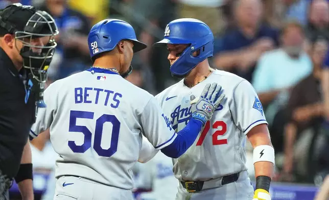 Los Angeles Dodgers' Miguel Rojas, right, congratulates Mookie Betts as he crosses home plate after hitting a solo home run off Colorado Rockies starting pitcher Kyle Freeland in the fourth inning of a baseball game Wednesday, Aug. 19, 2026, in Denver. (AP Photo/David Zalubowski)