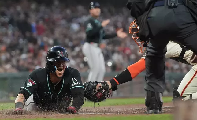 Arizona Diamondbacks' Ildemaro Vargas, left, slides home to score past San Francisco Giants catcher Andrew Knizner during the third inning of the second baseball game of a doubleheader, Saturday, Aug. 29, 2026, in San Francisco. (AP Photo/Jeff Chiu)