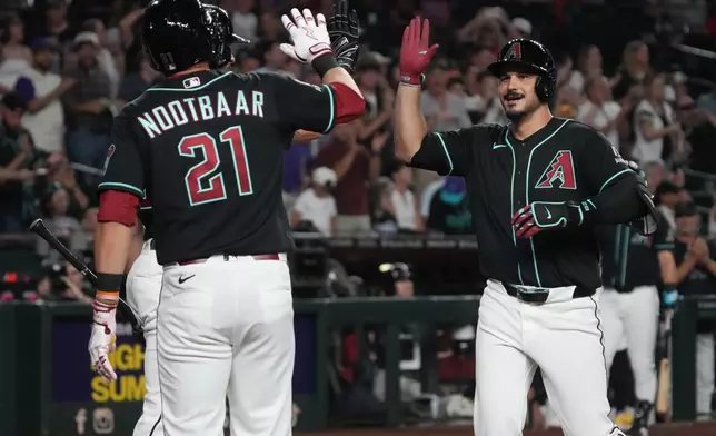 Arizona Diamondbacks' Nolan Arenado, right, celebrates with Tyler Locklear, back left, and Lars Nootbaar (21) after hitting a grand slam against the Colorado Rockies in the second inning of a baseball game, Monday, Aug 10, 2026, in Phoenix. (AP Photo/Rick Scuteri)