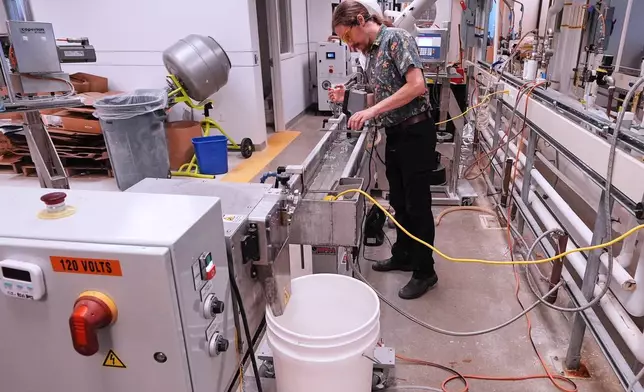 Lab technician Fen Spinney calibrates a machine that is used in compounding bioplastic pellets at CJ Biomaterials, Monday, Aug. 3, 2026, in Woburn, Mass. (AP Photo/Charles Krupa)