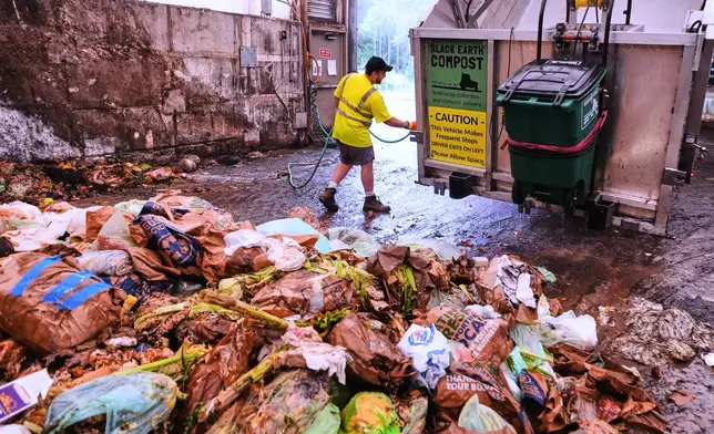 Paul Milonopolous rinses out the dump box after offloading fresh organic matter, which included biodegradable cups, cutlery and bin liners that were mixed in with food scraps and lobster shells, that will be used to make compost at Black Earth Compost, Monday, Aug. 3, 2026, in Manchester-by-the-Sea, Mass. (AP Photo/Charles Krupa)
