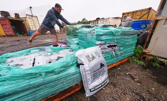 Justin Sandler adds a bag of compost to a pallet at Black Earth Compost, Monday, Aug. 3, 2026, in Manchester-by-the-Sea, Mass. (AP Photo/Charles Krupa)