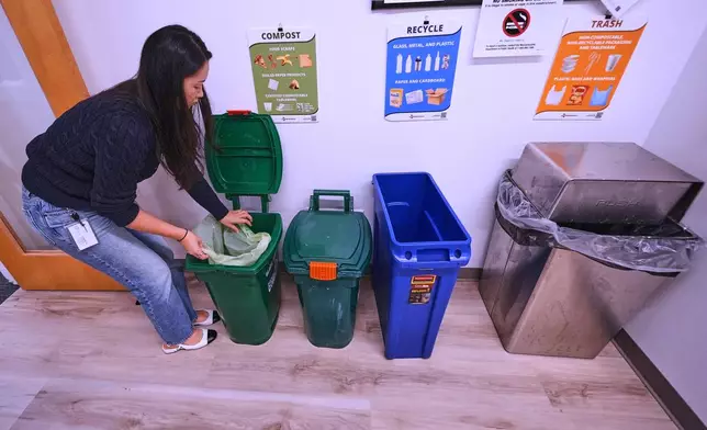 Katie Byun places a biodegradable bag into a compost collection bin in the lunch room at CJ Biomaterials, Monday, Aug. 3, 2026, in Woburn, Mass. (AP Photo/Charles Krupa)