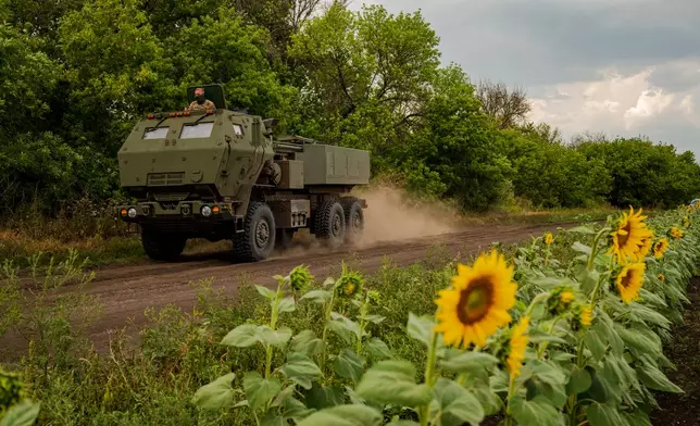A member of a Ukrainian HIMARS crew, attached to the 148th brigade, peers from the vehicle driving along the front line in eastern Ukraine, on its way to fire rockets at Russian positions, Saturday, Aug. 8, 2026. (AP Photo/Dan Bashakov)