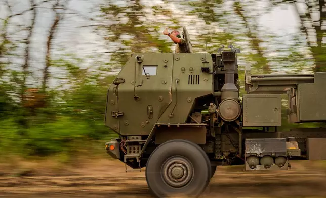 A member of a Ukrainian HIMARS crew, attached to the 148th brigade, gives a thumbs up as the vehicle speeds to evade detection by reconnaissance drones along the front line in eastern Ukraine, on its way to fire rockets at Russian positions, Saturday, Aug. 8, 2026. (AP Photo/Dan Bashakov)