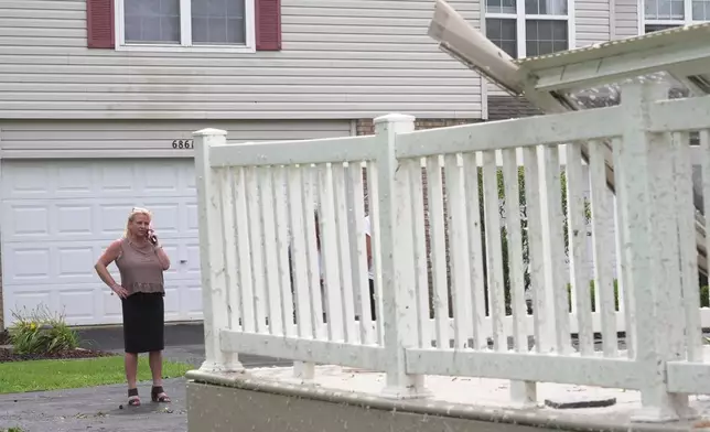 Kerry Hourigan speaks on the phone after reviewing damage a storm caused to her home in Tinley Park, Ill., Tuesday, Aug. 11, 2026. (AP Photo/Laura Bargfeld)