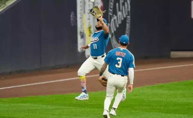 Milwaukee Brewers left fielder Jackson Chourio (11) catches a pop fly hit by Atlanta Braves' Ozzie Albies as Brewers third baseman Joey Ortiz (3) looks on during the fourth inning of a baseball game against Friday, Aug. 21, 2026, in Milwaukee. (AP Photo/Kayla Wolf)