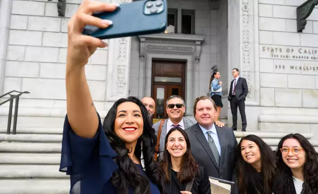 Plaintiff Clarissa Cervantes takes a selfie with legal team members before attending a hearing about Riverside County Sheriff Chad Bianco's seizure and recount of more than half a million 2025 election ballots on Monday, Aug. 24, 2026, in San Francisco. (AP Photo/Noah Berger)