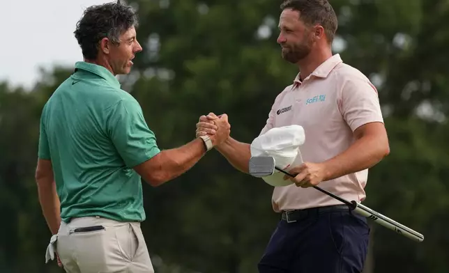 Rory McIlroy, of Northern Ireland, speaks with Wyndham Clark as Clark wins the final round of the BMW Championship golf tournament, Sunday, Aug. 23, 2026, in St. Louis. (AP Photo/Jeff Roberson)