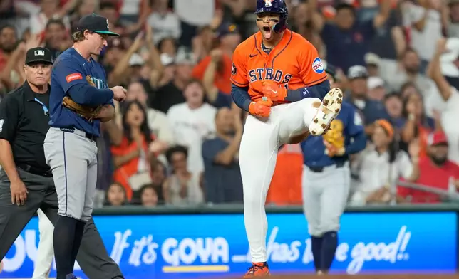 Houston Astros' Cam Smith, right, celebrates after hitting a RBI triple as Seattle Mariners third baseman Brendan Donovan looks on during the second inning of a baseball game Friday, Aug. 14, 2026, in Houston. (AP Photo/David J. Phillip)