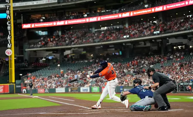 Houston Astros' Yordan Alvarez (44) hits a home run as Seattle Mariners catcher Cal Raleigh reaches for the pitch during the first inning of a baseball game Friday, Aug. 14, 2026, in Houston. (AP Photo/David J. Phillip)