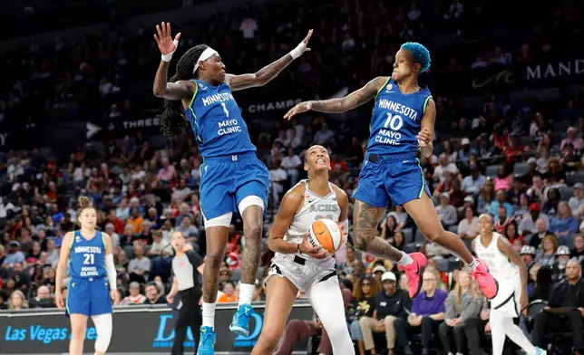Minnesota Lynx forward Natasha Howard (1) and guard Courtney Williams (10) jump in an attempt to block a shot by Las Vegas Aces center A'ja Wilson during the first half of a WNBA basketball game Saturday, Aug. 15, 2026, in Las Vegas. (Steve Marcus/Las Vegas Sun via AP)