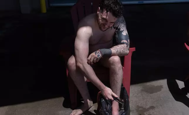 Jacob Hemann grimaces as he adds hot water to a bucket as he gets treatment for a stingray sting at Bolsa Chica State Beach in Huntington Beach, Calif., Friday, July 24, 2026. (AP Photo/Jae C. Hong)
