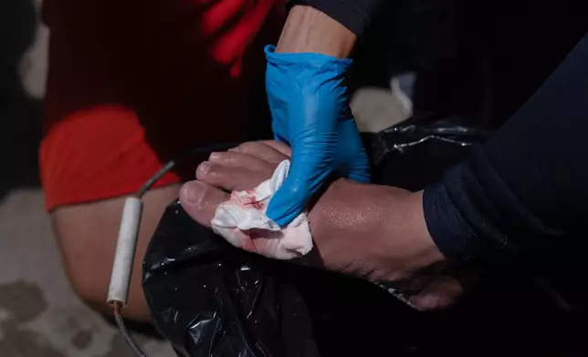 Lifeguard Max Voci applies gauze to a beachgoer's foot to treat a stingray sting at Bolsa Chica State Beach in Huntington Beach, Calif., Friday, July 24, 2026. (AP Photo/Jae C. Hong)