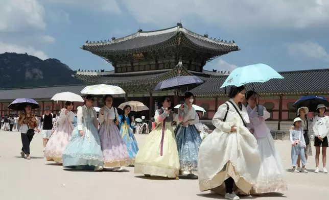 Visitors holding umbrellas to avoid sunshine leave the Gyeongbok Palace in Seoul, South Korea, Wednesday, Aug. 5, 2026. (AP Photo/Ahn Young-joon)