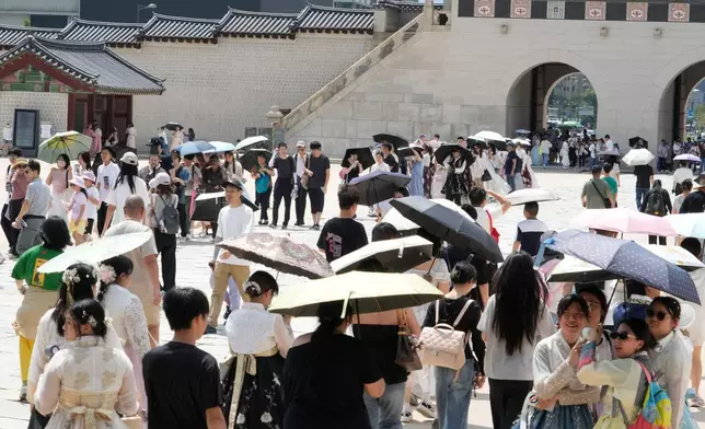 Visitors hold umbrellas to avoid sunshine at the Gyeongbok Palace in Seoul, South Korea, Wednesday, Aug. 5, 2026. (AP Photo/Ahn Young-joon)