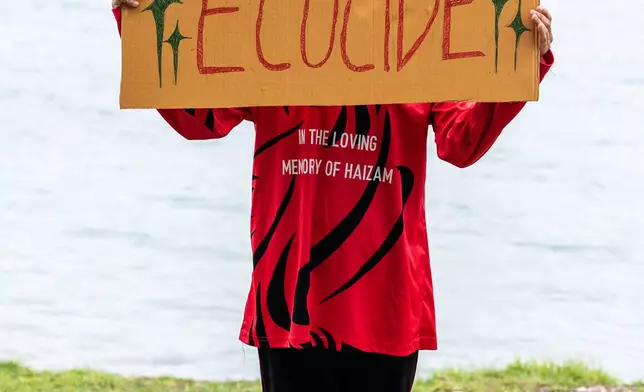 A demonstrator holds a sign while participating in an action as part of Project ThimaaVeshi, a youth-led protest against ongoing reclamation projects damaging mangroves, in Addu City, Maldives, June 3, 2026. (AP Photo/Sophia Nasif)