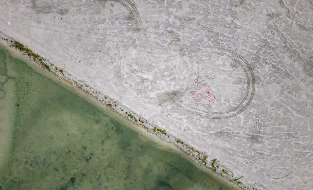 "Eccocide in Addu" is displayed on reclaimed land by Project ThimaaVeshi, a youth left group, as part of a demonstration against ongoing reclamation projects in Addu City, Maldives, June 3, 2026. (AP Photo/Sophia Nasif)